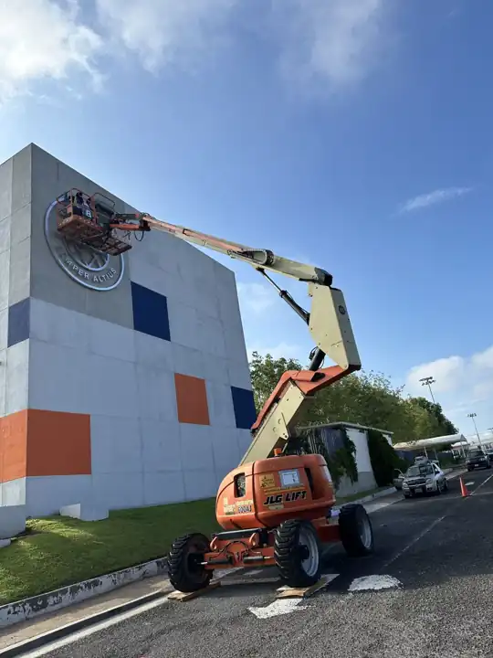 Grúa instalando logotipo en fachada